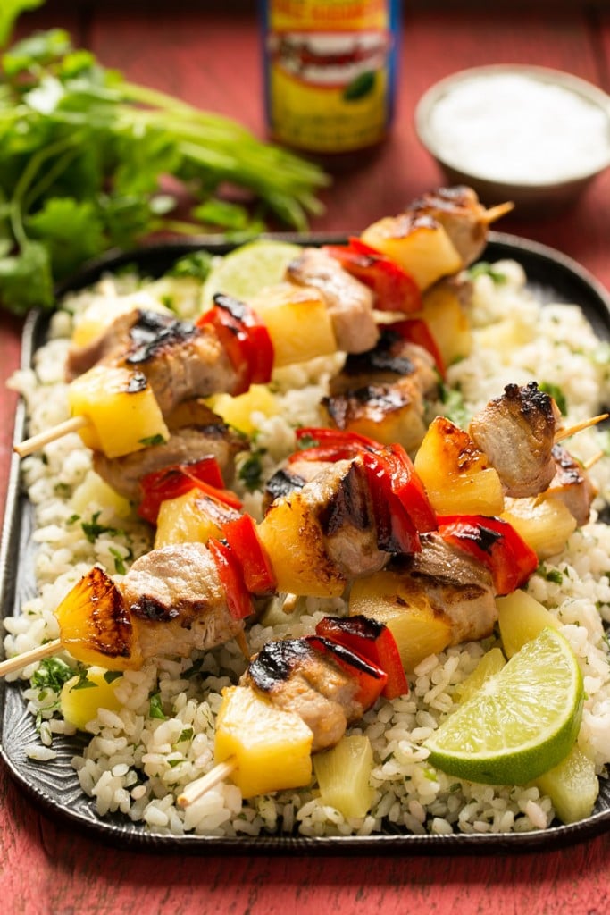 A recipe for sweet and spicy pineapple pork kabobs served on a bed of pineapple cilantro rice. Ad