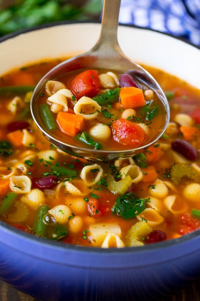 A ladle serving up a portion of classic minestrone soup.