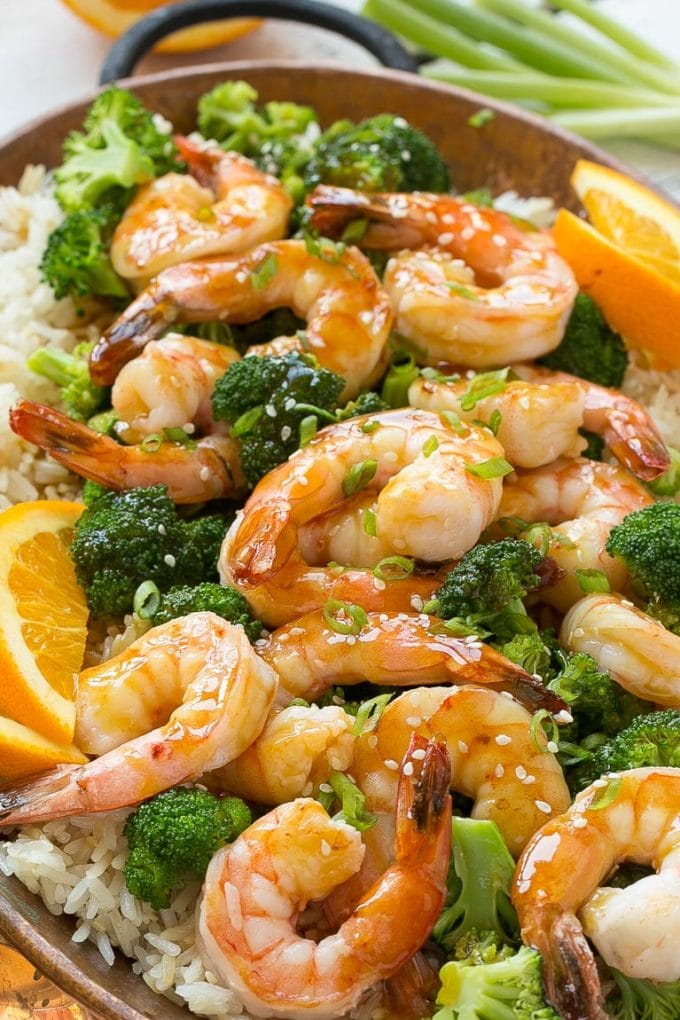 Shrimp and broccoli topped with sauce and garnished with oranges.
