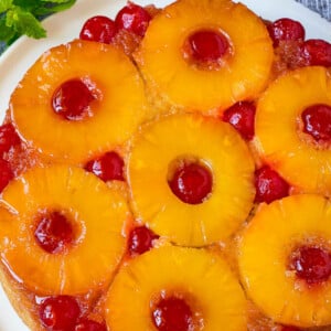 Pineapple upside down cake on a serving platter, garnished with fresh mint.