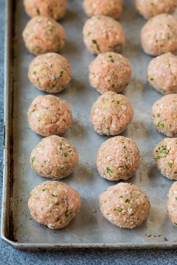Raw meatballs on a sheet pan.
