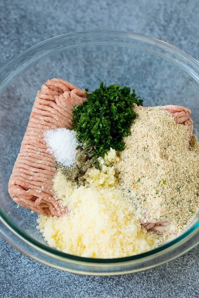 Ground turkey with breadcrumbs, herbs, seasonings and cheese in a bowl.