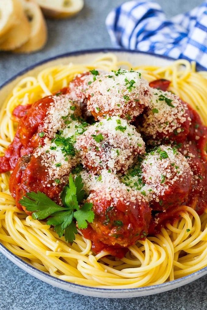 A bowl of spaghetti and meatballs topped with parmesan cheese.