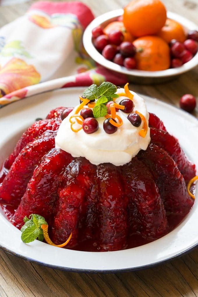 Cranberry Jello salad in a serving dish topped with whipped cream and orange zest.
