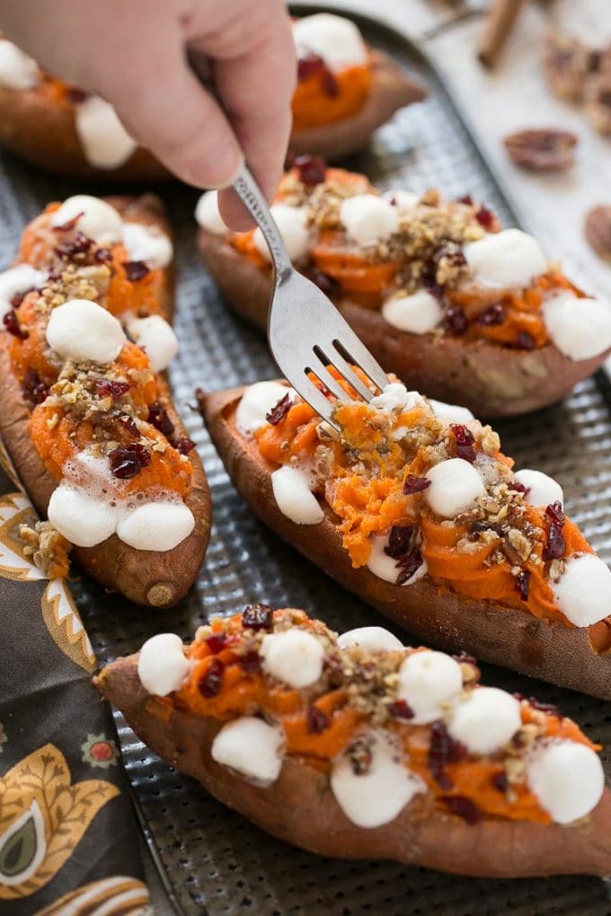 A fork lifting some of the mashed filling and toppings out of the cooked spuds. 