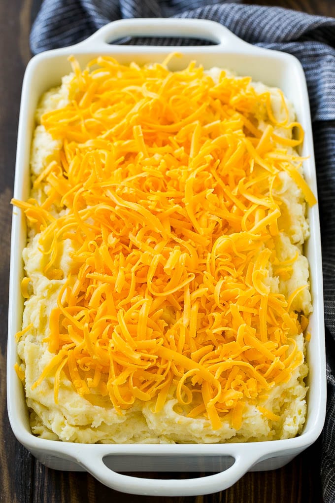 Mashed potatoes in a casserole dish, topped with shredded cheese.