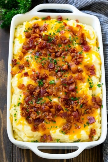 Loaded mashed potato casserole topped with melted cheese, bacon and herbs.