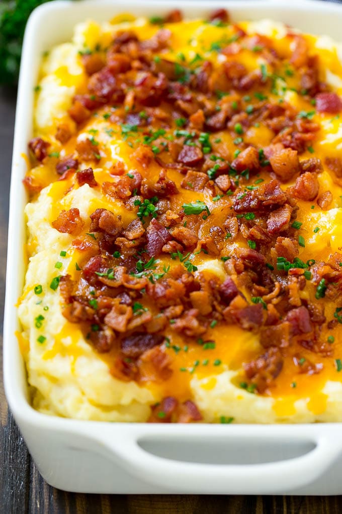 A casserole of loaded mashed potatoes topped with cheddar cheese, crispy bacon and chives.