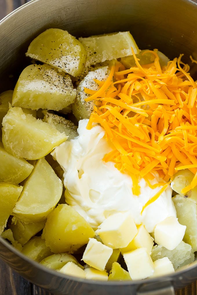 Potatoes, sour cream, cheese and seasonings in a bowl.