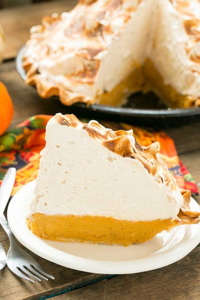 A cut slice of pumpkin meringue pie on a plate.