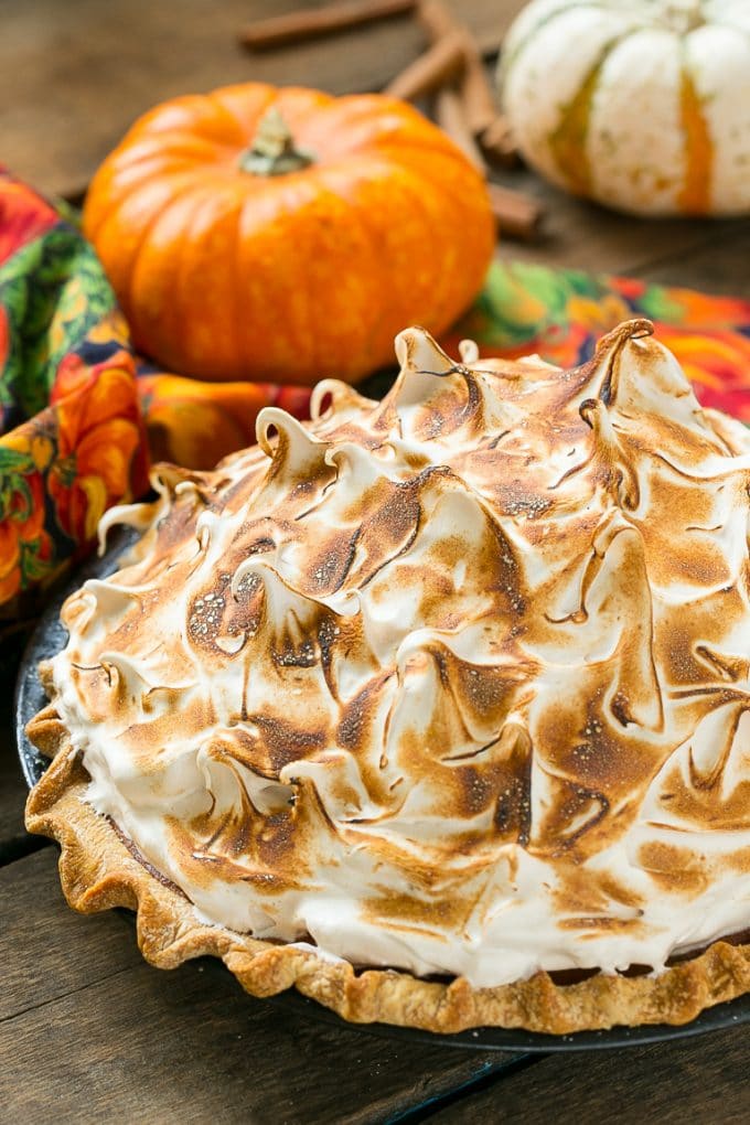 A pumpkin meringue pie on a table with fall decorations.