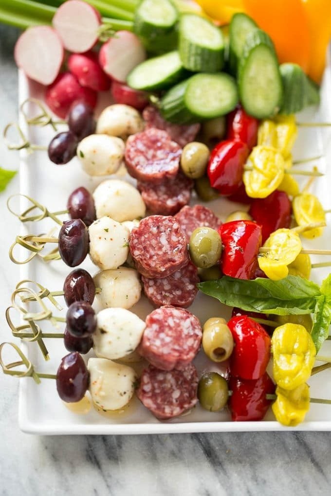 A tray of antipasto kabobs with meat, olives and vegetables.