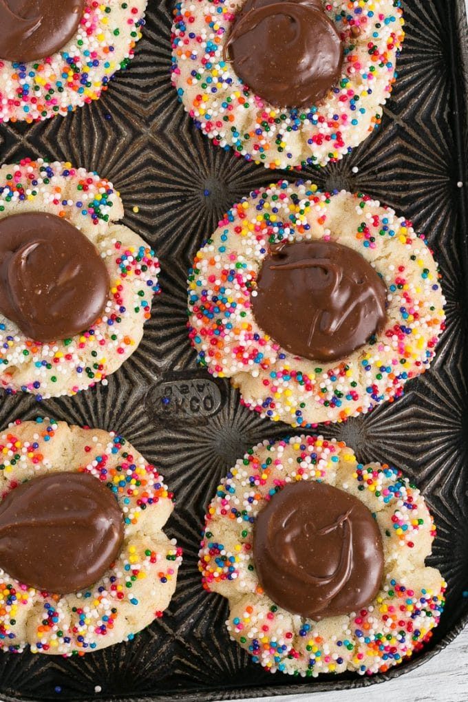 A sheet pan of sprinkle cookies topped with chocolate.