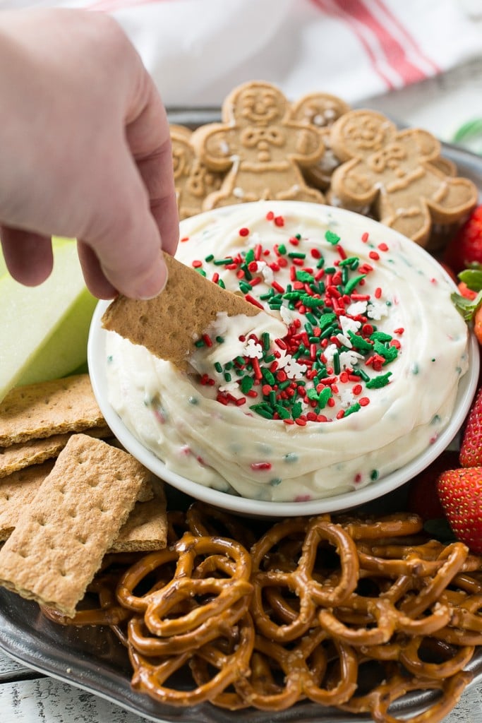 This Christmas cookie dough dip has a fluffy and creamy base that's swirled with plenty of holiday sprinkles and served with fruit and cookies for dipping. It only takes 5 minutes to make! #HolidayWithChobani Ad