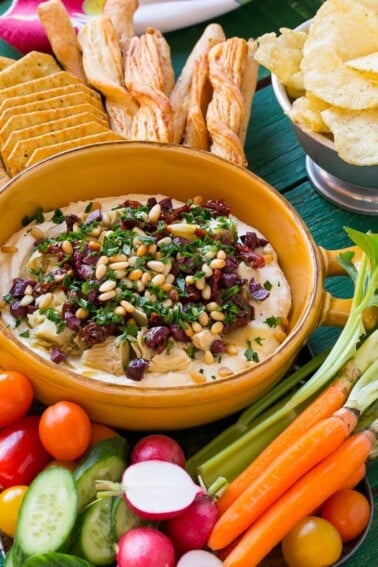 This mediterranean layered dip starts with a base of whipped feta cheese and is topped with artichokes, olives, sun dried tomatoes and pine nuts. Ready in about 10 minutes, it's the perfect party appetizer!