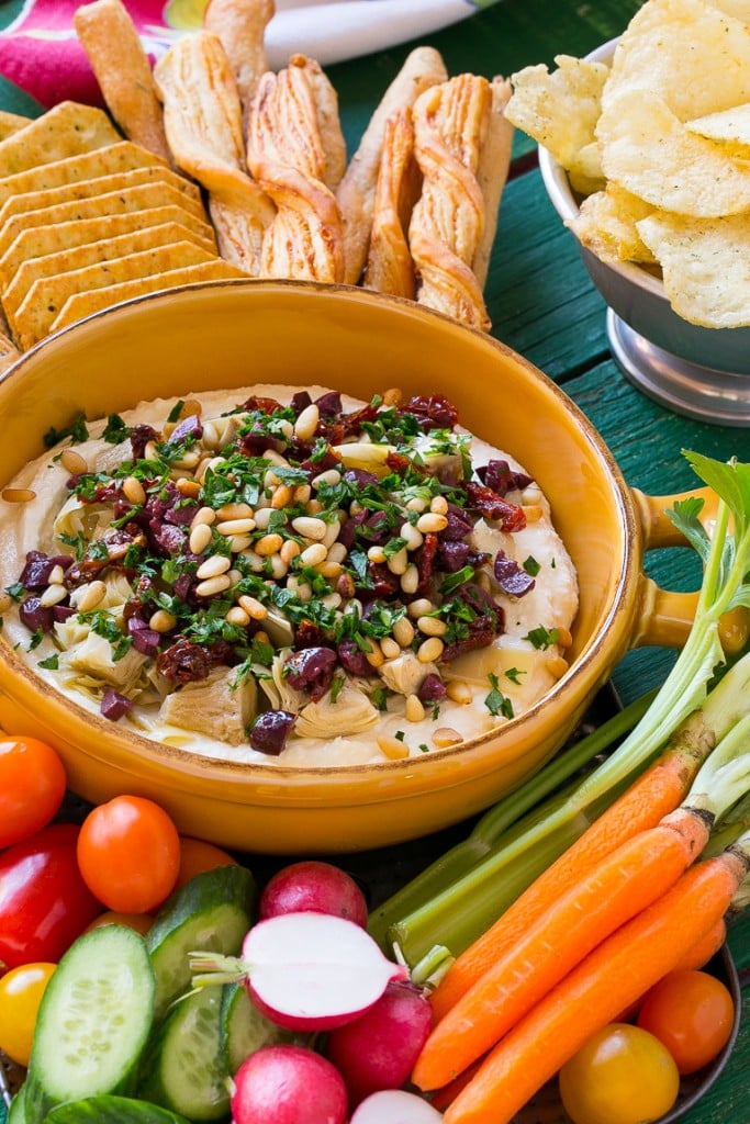 This mediterranean layered dip starts with a base of whipped feta cheese and is topped with artichokes, olives, sun dried tomatoes and pine nuts. Ready in about 10 minutes, it's the perfect party appetizer!