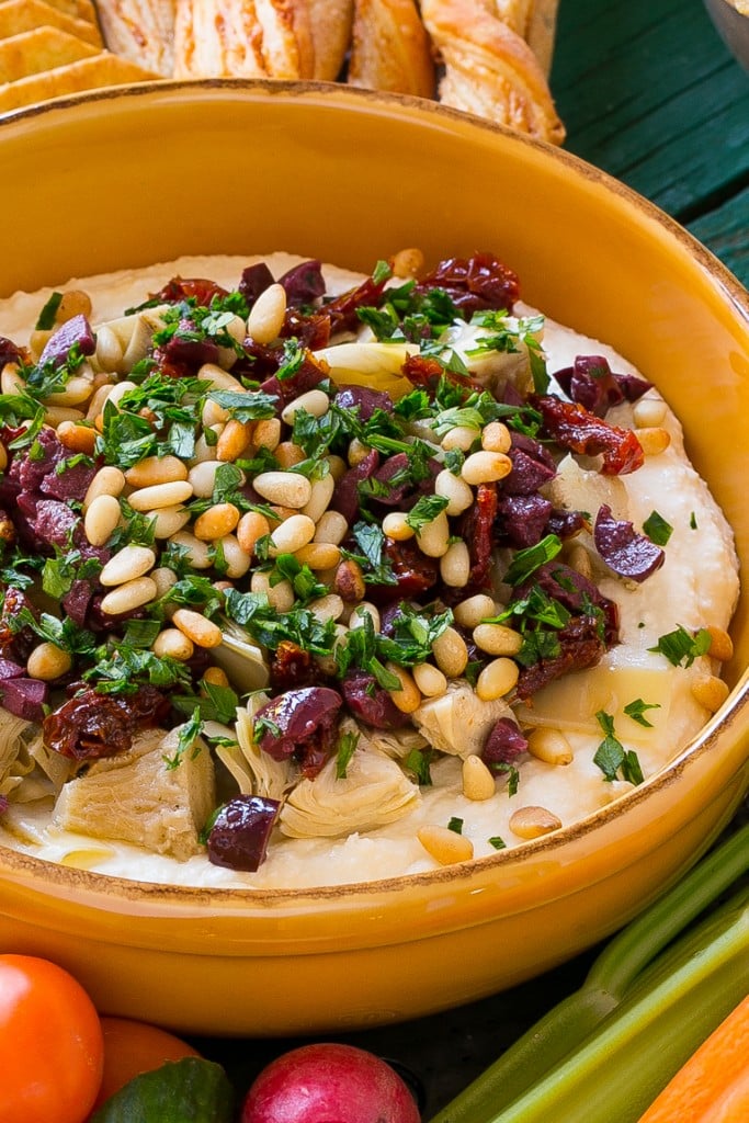 This mediterranean layered dip starts with a base of whipped feta cheese and is topped with artichokes, olives, sun dried tomatoes and pine nuts. Ready in about 10 minutes, it's the perfect party appetizer!