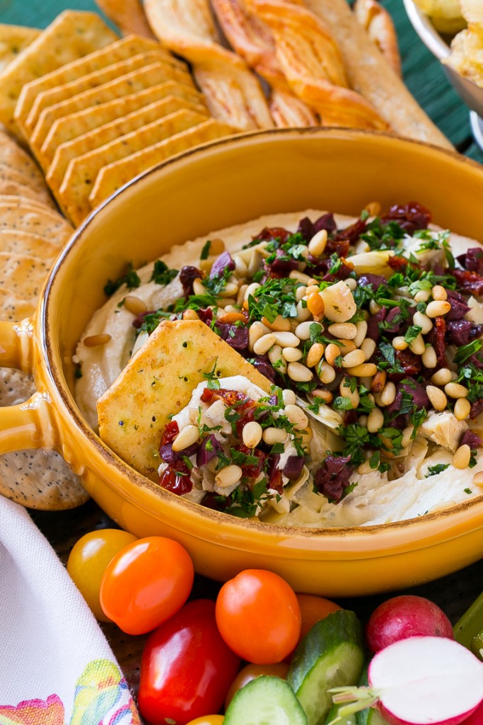 This mediterranean layered dip starts with a base of whipped feta cheese and is topped with artichokes, olives, sun dried tomatoes and pine nuts. Ready in about 10 minutes, it's the perfect party appetizer!
