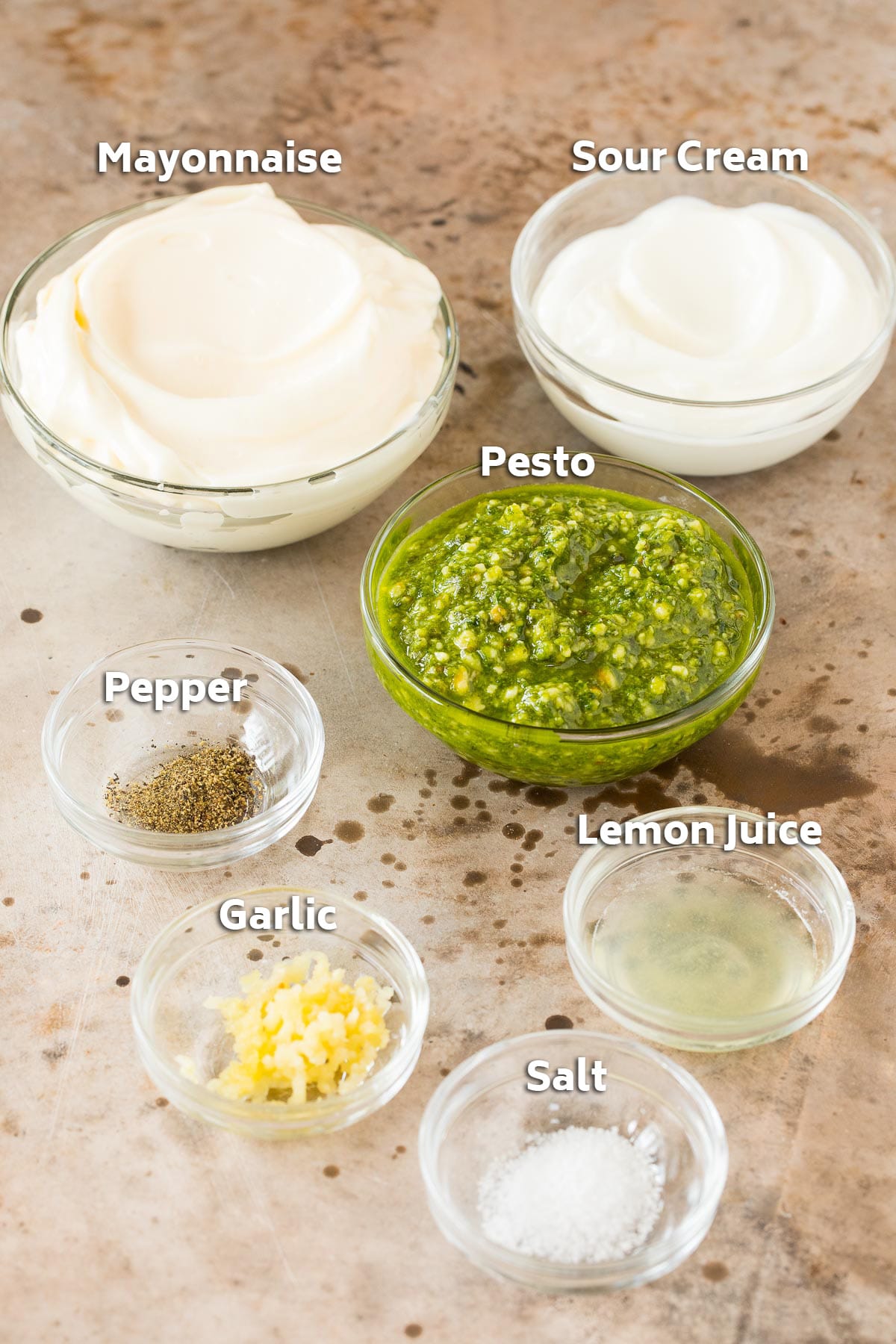Bowls of mayonnaise, sour cream, pesto and seasonings.