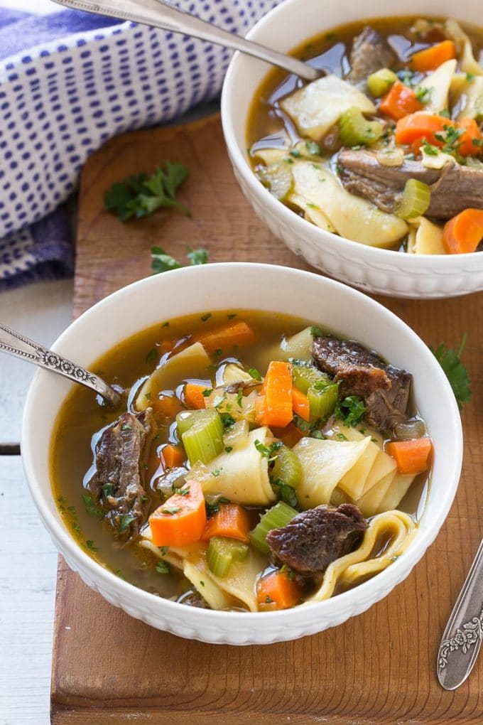 Two bowls of beef noodle soup with braised beef and veggies.