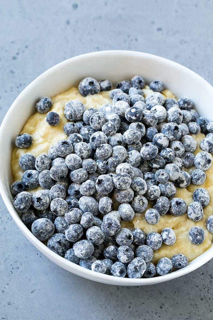 A bowl of banana bread batter with fresh blueberries on top.