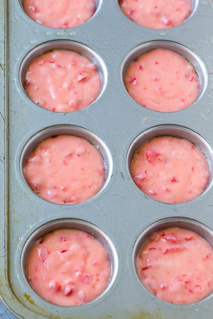 Cherry muffin batter inside muffin tins.