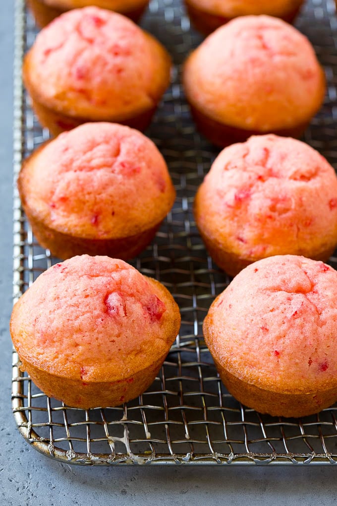 Baked cherry muffins on a cooling rack.