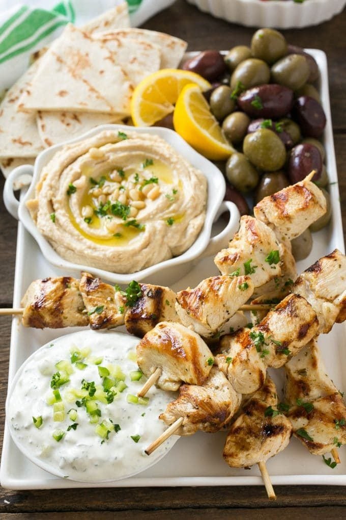 Chicken souvlaki skewers marinated in lemon and herbs, then grilled. Served with olives, hummus and pita bread.