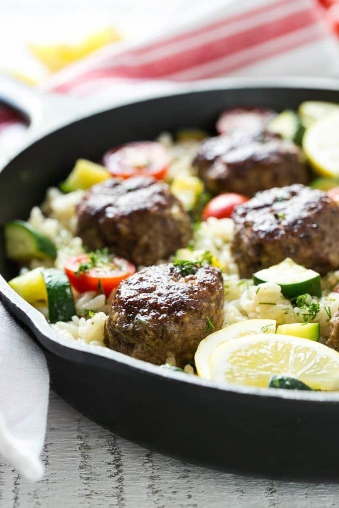 A pan of Greek style meatballs with lemon rice and fresh tomatoes.