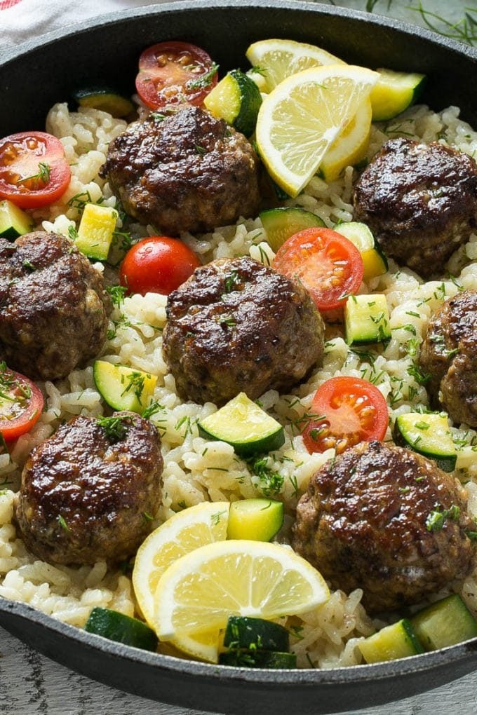 Baked meatballs in a skillet with rice, cherry tomatoes and zucchini.