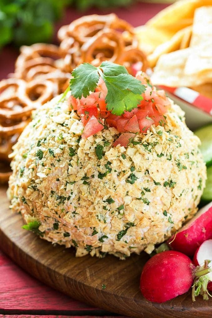 A jalapeno cheese ball coated in tortilla chips and topped with diced tomatoes.