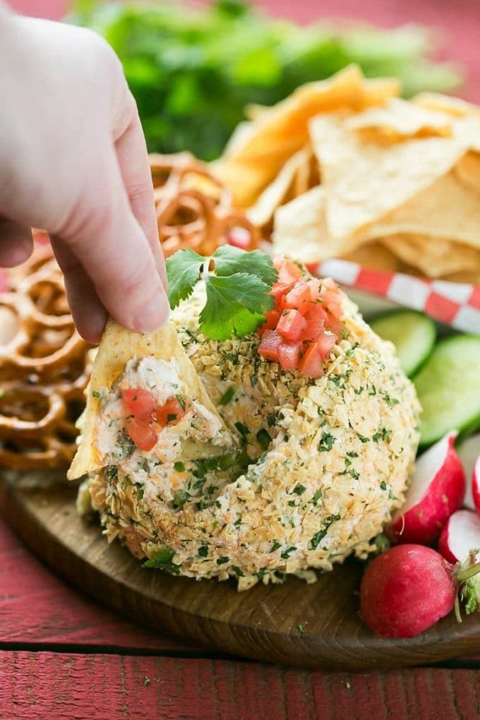 A chip scooping out a portion of cheese ball.