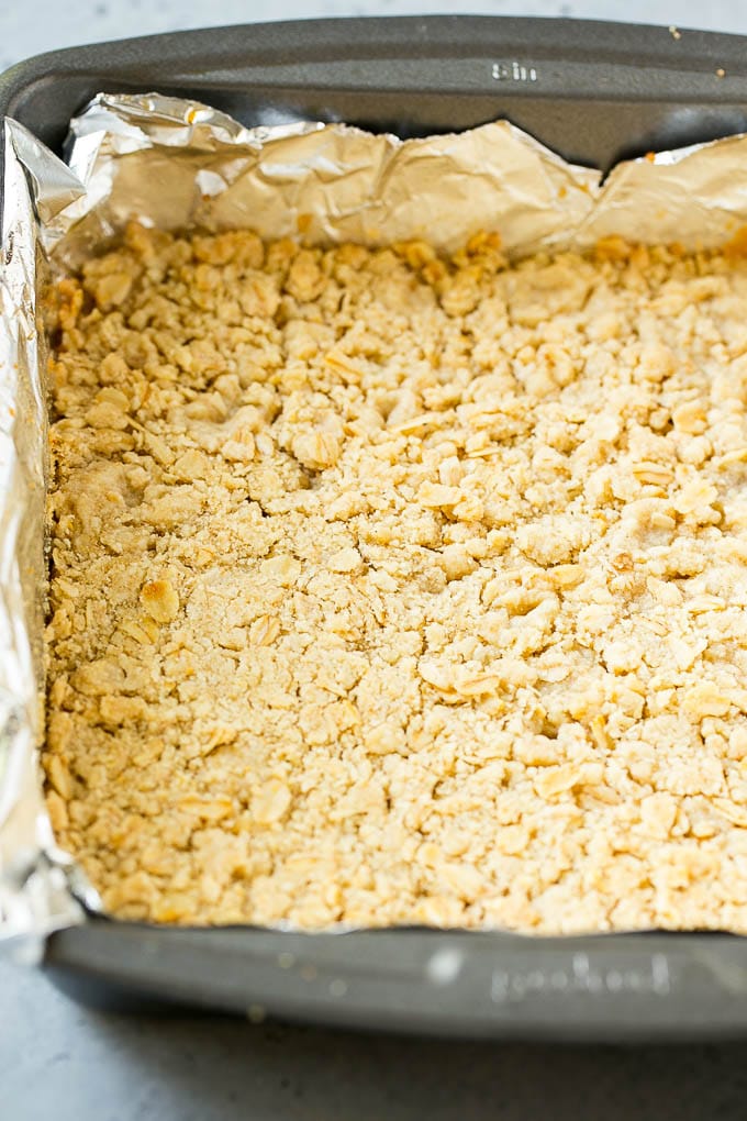 An oatmeal and brown sugar crust pressed into a pan.