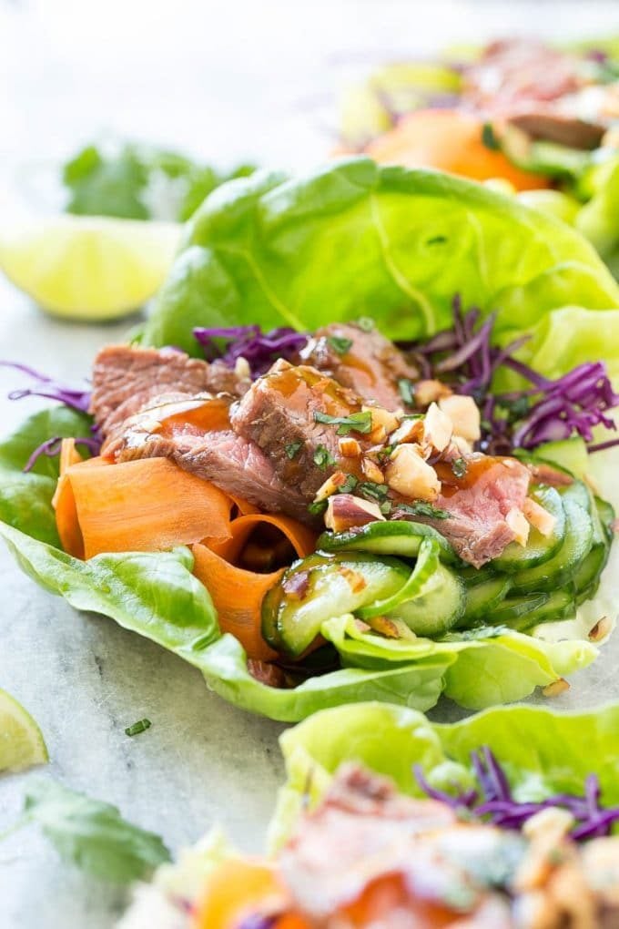 Beef lettuce wraps with seared steak, carrots, cucumbers and savory sauce.