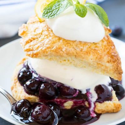This recipe for blueberry shortcake is vanilla ice cream and homemade blueberry sauce sandwiched between lemon shortcake and finished off with whipped cream. This easy and elegant dessert is perfect for any occasion!