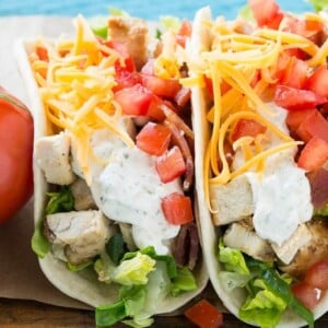 This recipe for chicken ranch tacos is grilled chicken with bacon, homemade ranch sauce, cheese and fresh vegetables, all stuffed inside warm flour tortillas. A family friendly meal that's simple to make and fun to eat!