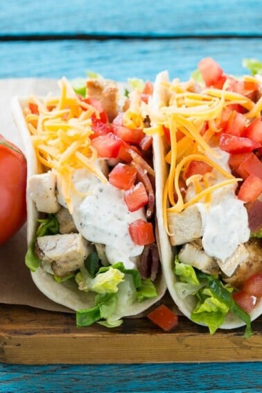 This recipe for chicken ranch tacos is grilled chicken with bacon, homemade ranch sauce, cheese and fresh vegetables, all stuffed inside warm flour tortillas. A family friendly meal that's simple to make and fun to eat!