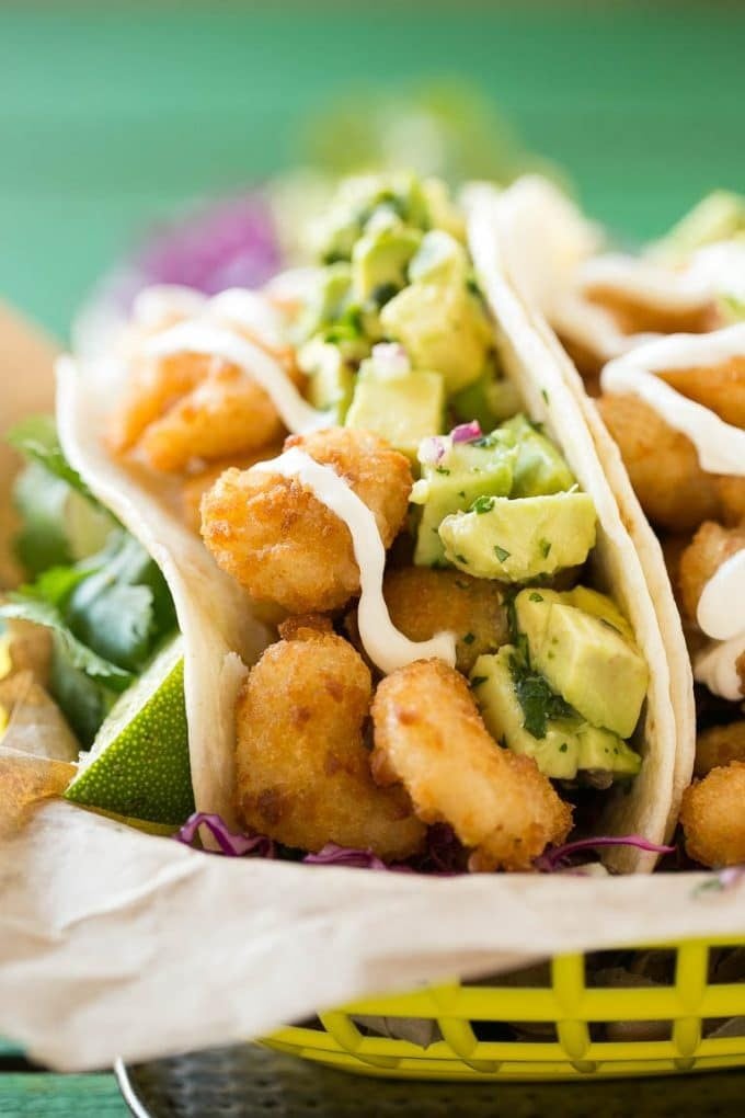 Fried shrimp tacos in flour tortillas with avocado and sour cream.