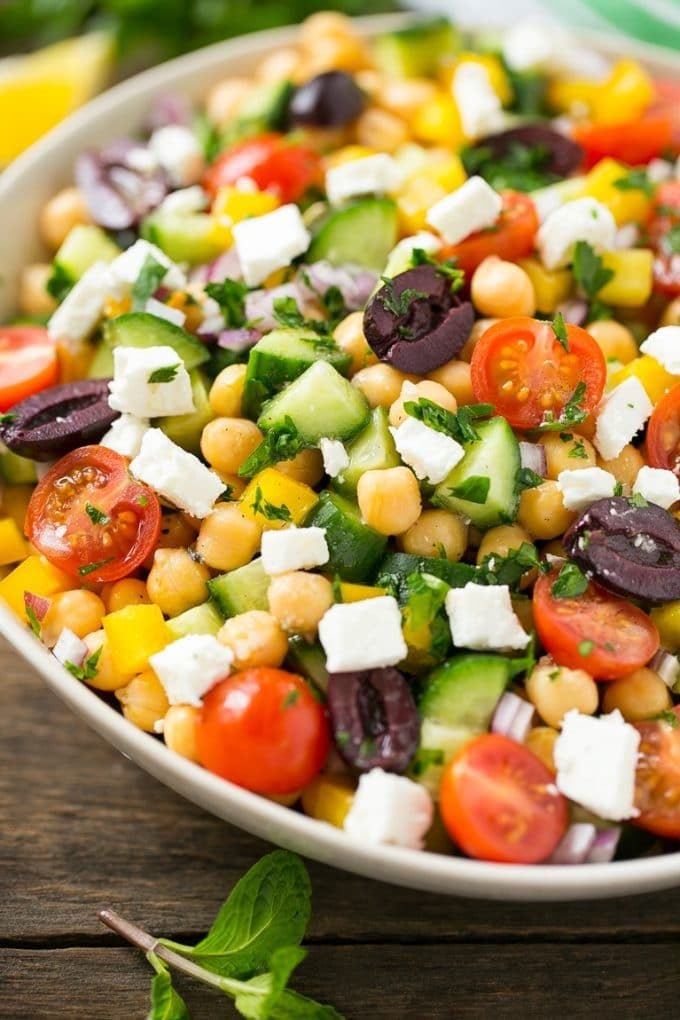 Cucumbers, chickpeas, olives, tomatoes, peppers and feta cheese in a serving bowl.