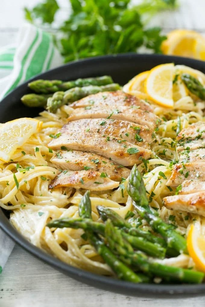 A skillet with lemon asparagus pasta, cream sauce and sliced grilled chicken.