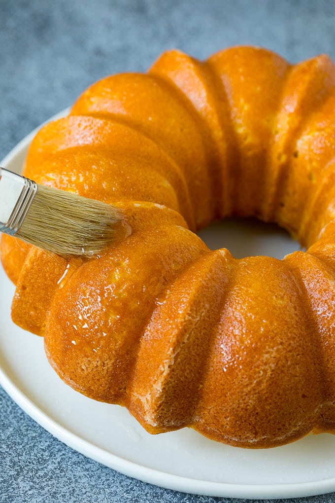 A brush adding lemon syrup to a bundt cake.