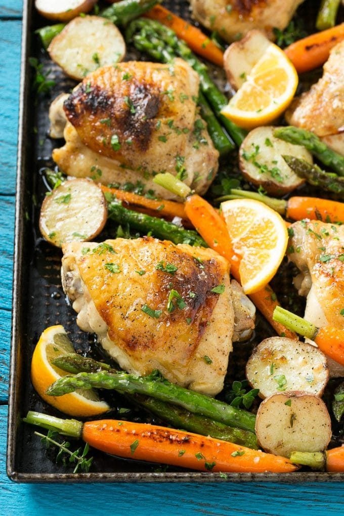 A sheet pan full of lemon thyme chicken thighs, potatoes and vegetables.