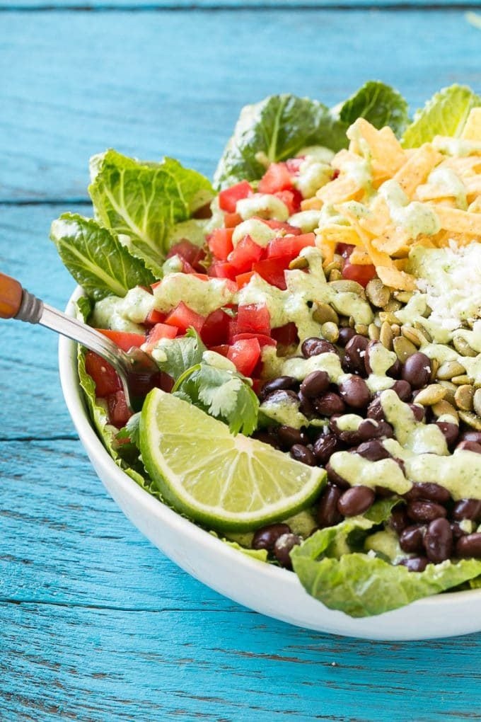 A fork in a bowl of Mexican style Caesar salad.