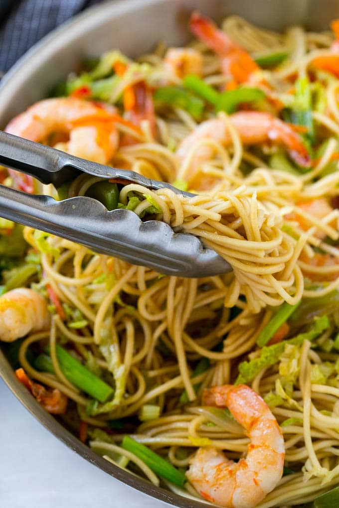 A pile of chow mein noodles with shrimp and veggies.