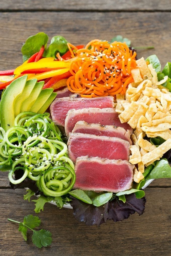 A bed of greens with seared tuna, carrots, cucumber and wonton strips.