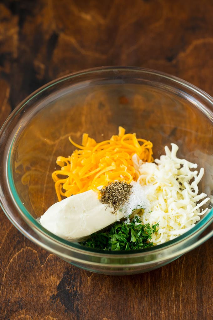 Three types of cheese, parsley and seasonings in a bowl.