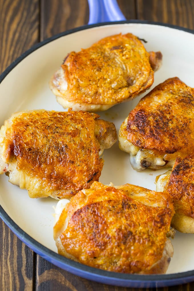 Browned chicken thighs in a skillet.