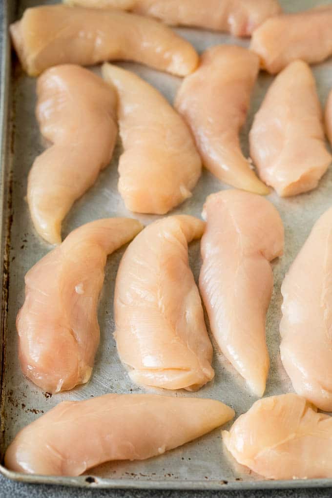 Chicken breast tenders on a sheet pan.