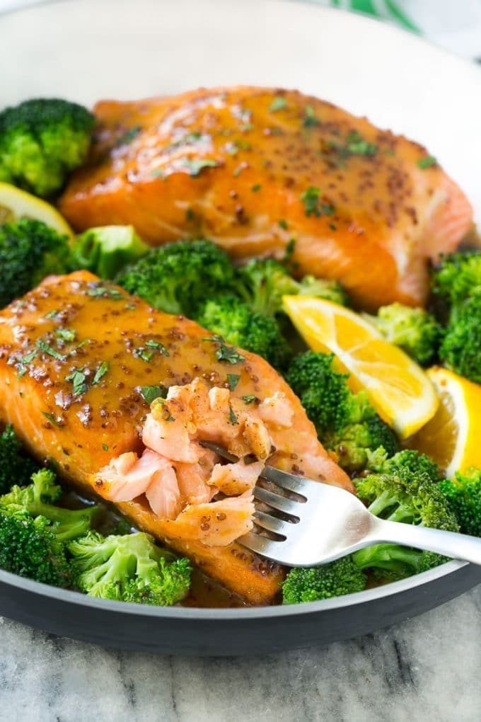 A pan of honey mustard salmon with broccoli and a fork cutting into the fish.