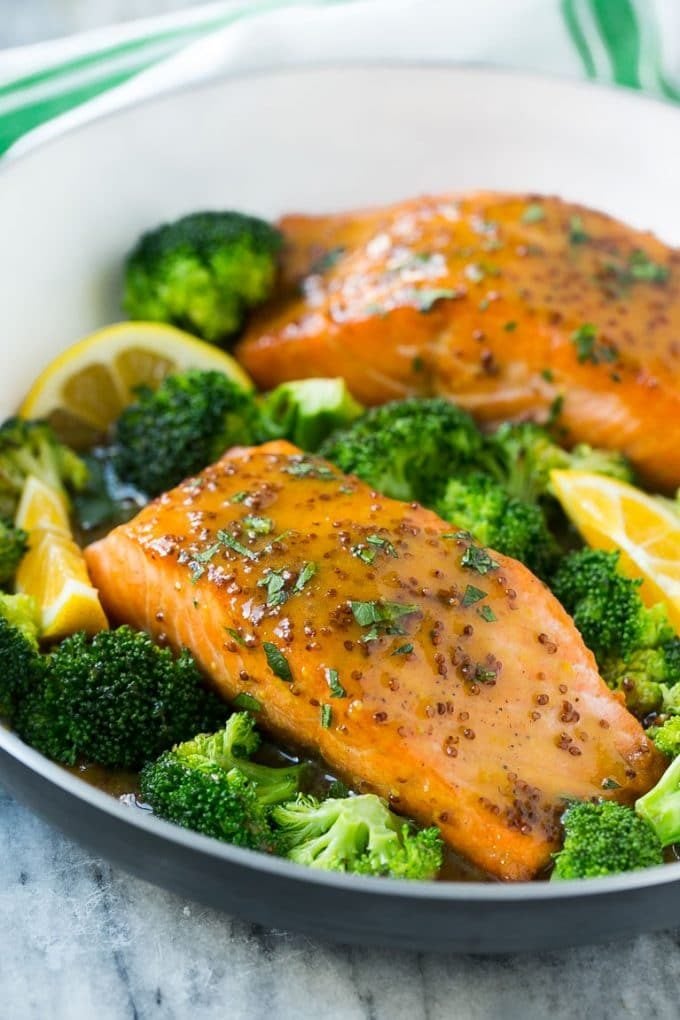 A pan of honey mustard salmon fillets surrounded by broccoli florets.